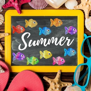 Detail of glitter fish stickers on a blackboard with summer themed beach decorations