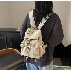 Beige drawstring nylon backpack shown from a back-view perspective on a female model