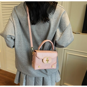 Détail du mini sac carré en cuir rose avec boucle dorée et bandoulière amovible