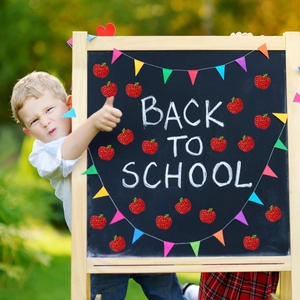 Glittery red apple stickers with green leaves on blackboard for back to school decoration