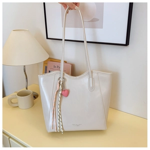 Macro detail of beige faux leather tote bag with elegant heart charm and sleek logo