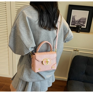 Détail d'un sac à main en cuir gaufré rose clair avec boucle dorée et rivets en métal
