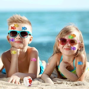 Macro shot of colorful glitter fish stickers on children during outdoor beach activities