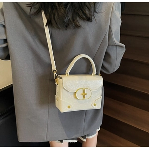 Détail d'un petit sac en cuir verni beige froissé avec fermoir rotatif ovale doré