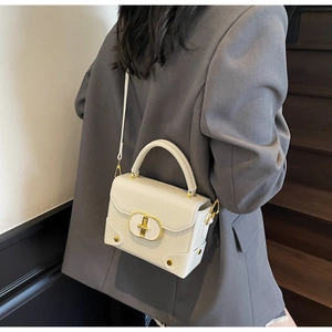 Détail du sac à main blanc cassé avec fermoir doré métallique et texture de cuir grainé