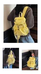 Detail view of a pale yellow nylon drawstring backpack with side pockets and a flap cover