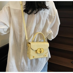 Sac à main chic en cuir texturé jaune pâle porté par un mannequin dans un escalier