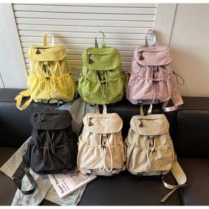 Close-up of nylon drawstring backpacks in multiple colors with flap pockets and side pouches