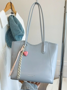 Large light blue leather tote bag with shoulder straps and heart charm in a lifestyle set