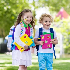 Cute apple-shaped stickers used on kids faces and notebooks in an outdoor setting