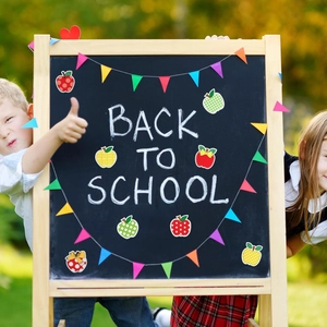 Colorful apple shaped back to school stickers on a blackboard in a classroom setting