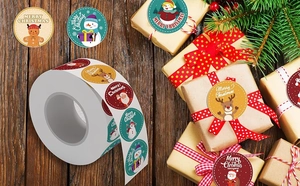 Close-up of Merry Christmas roll stickers featuring Santa and Snowman on a gift box