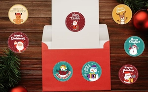 Detailed view of round Christmas stickers on red envelope with festive snowman and reindeer
