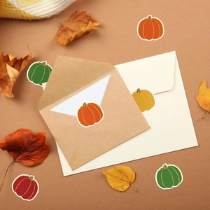 Detail of pumpkin shaped decorative stickers on envelopes with autumn leaves background