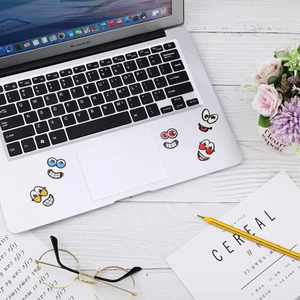 Close-up of five cute cartoon facial expression stickers on a laptop workspace