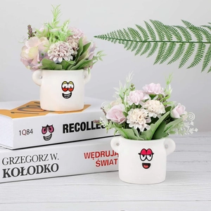 Detail of white ceramic smile planters with faux hydrangea and roses on books