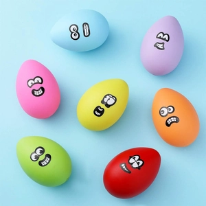 Overhead view of colorful matte egg-shaped cartoon stickers on a light blue surface