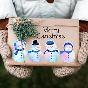 Holographic Christmas snowman stickers on a kraft gift box with festive pine and twine