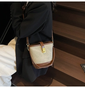 Close-up of contrast bucket bag with gold lock and premium brown leather handle detail