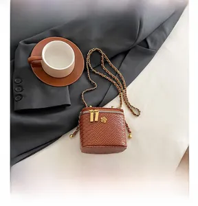 Detail view of brown snake-print mini crossbody bag with gold floral clasp and chain
