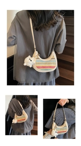 Detail of a rainbow woven crescent bag featuring cream leather trim and a cat charm