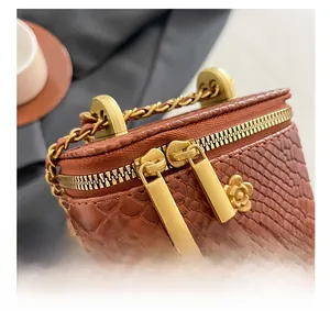 Detail of snake skin texture mini bag featuring dual gold zippers and flower pendants