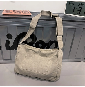 Detail of stone gray canvas messenger bag showing adjustable strap and side pocket design