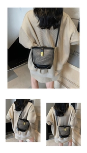 Detailed close-up of marble pattern bucket bag with golden metal buckle and leather strap