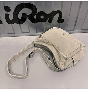Close-up of beige washed canvas messenger bag with adjustable strap and front pocket