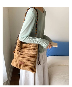 Detail of woven tote bag featuring beaded shoulder straps and side drawstring tassels