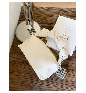 Detail of creamy white lychee grain leather bag with knotted handle and heart charm