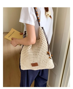Detail of crochet tote bag with wooden beads and minimalist leather brand patch