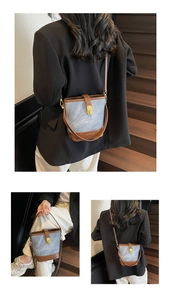 Detail view of vintage denim bucket bag with brown leather trim and golden hardware
