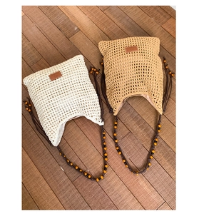 Detailed close-up of handmade woven hollow mesh tote bag with beaded shoulder straps