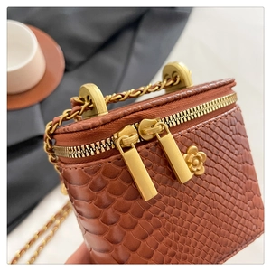 Macro detail of brown python texture mini square bag with gold camellia metal decor