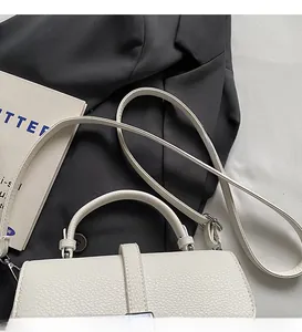 Detail of cream white lychee leather bag featuring smooth shoulder strap and silver hardware