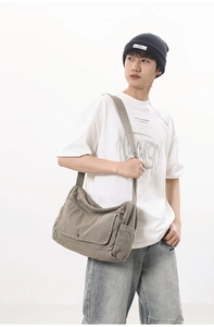 Detail showing the heavy washed canvas material and metal snap button of the messenger bag