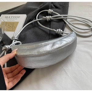 Detail of silver crescent bag featuring knotted straps and metallic crinkle finish