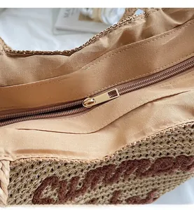 Close-up of smooth gold metal zipper and inner lining on a woven straw tote bag