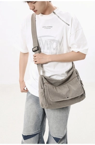 Detail view of washed canvas messenger bag showing rugged texture and wide shoulder strap