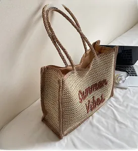 Close-up of woven straw tote bag featuring Summer Vibes embroidery and brown trim edges