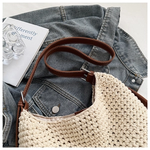 Detailed close-up of beige woven bucket bag with brown leather strap and silver buckle