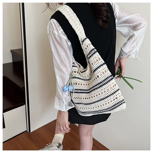 Detail view of woven knit tote bag featuring navy stripes and blue tulip charm decoration