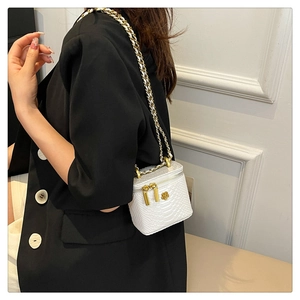 Detail of white snakeskin texture mini box bag with gold chain and floral metal buckle