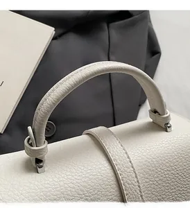 Detail of white lychee grain leather handbag with silver metal buckle and soft handle