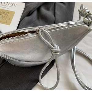 Detail shot of silver crescent moon bag with cracked leather texture and knotted strap