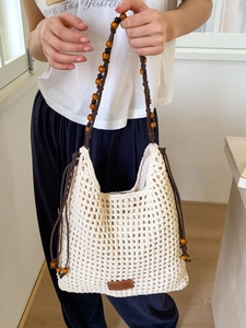 Beige woven straw tote bag with beaded shoulder straps for summer beach vacations