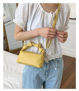 Detail of yellow cloud bag featuring unique knotted handle and grape-shaped metal charm