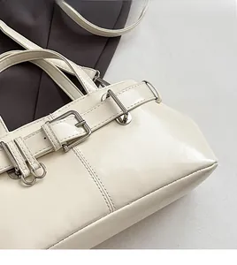 Dettaglio della borsa a mano color crema con fibbie in metallo argento e cinturini