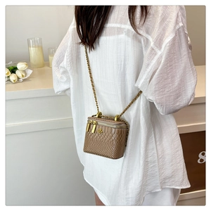 Detailed view of mini crossbody bag in brown snakeskin texture with gold chain and floral hardware